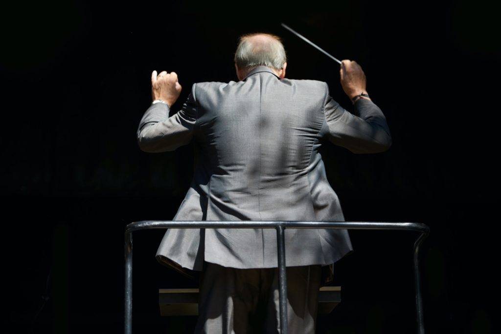 Guiding the music. Cropped rear view of an orchestra conductor waving his baton.