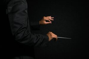 Orchestra conductor hands, Musician director holding stick on dark background